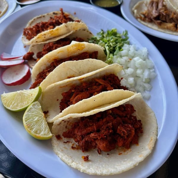 A plate of Cabaña Mexican Grill's al pastor tacos with limes, radishes, cilantro, and onions.